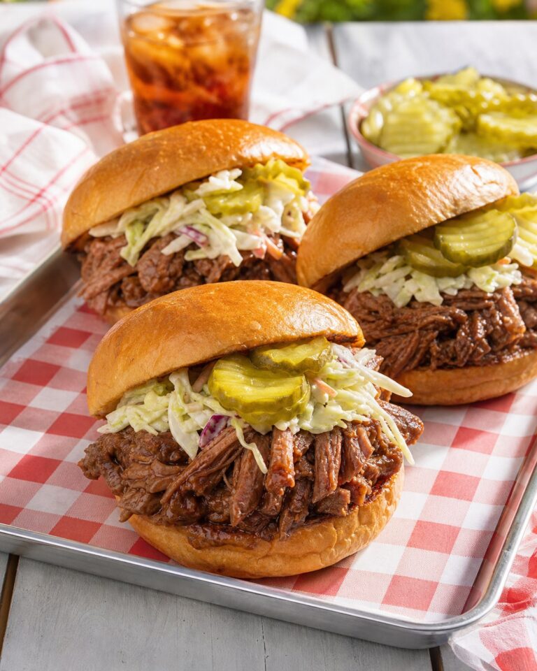 Pulled barbecue beef sandwiches topped with creamy slaw and pickle chips on brioche buns